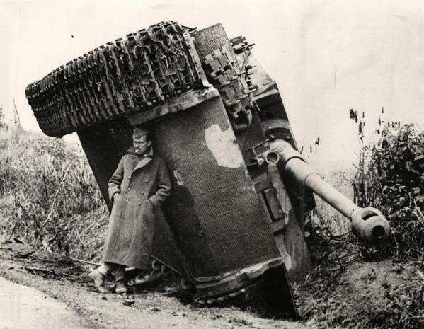 Un soldato britannico nascondersi dalla pioggia sotto un carro armato rovesciato. Italia, 1944