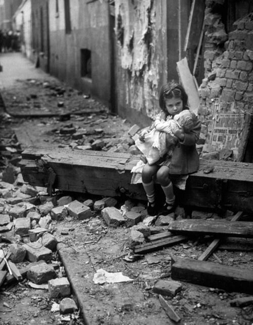 Una bambina inglese conforta la sua bambola tra le macerie della sua casa colpita dalle bombe nel 1940
