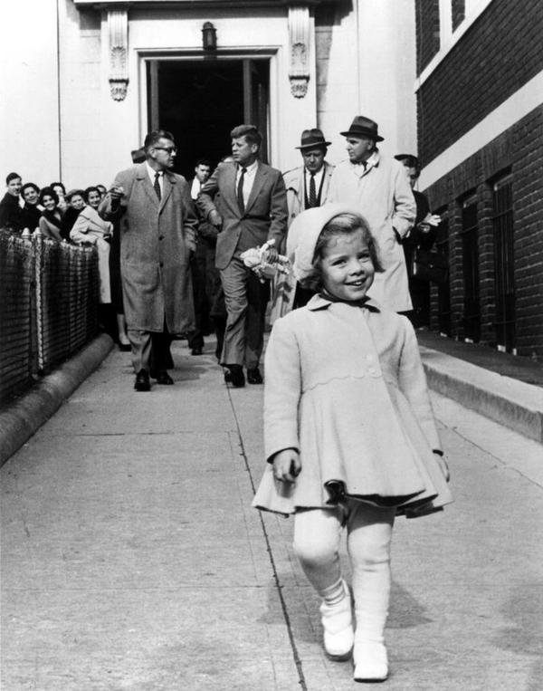 Caroline Kennedy cammina avanti mentre suo padre, JFK, porta la sua bambola. 1 gennaio 1963