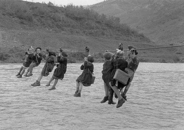Bambini attraversano il fiume con pulegge per arrivare a scuola nella periferia di Modena, Italia, 1959
