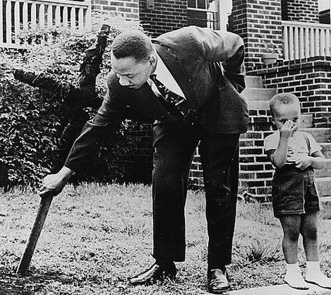 Martin Luther King Jr. rimuove una croce bruciata dal suo cortile con il figlio al suo fianco, 1960