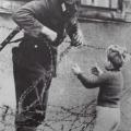 Un soldato tedesco dell’est che aiuta un bambino ad attraversare il Muro di Berlino appena costruito,1961