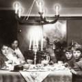 Una famiglia a Natale all’ora del tè con torta al cioccolato, un candelabro e agrifoglio sul tavolo. (Photo by Agenzia fotografica Generale: Getty Images). circa 1935