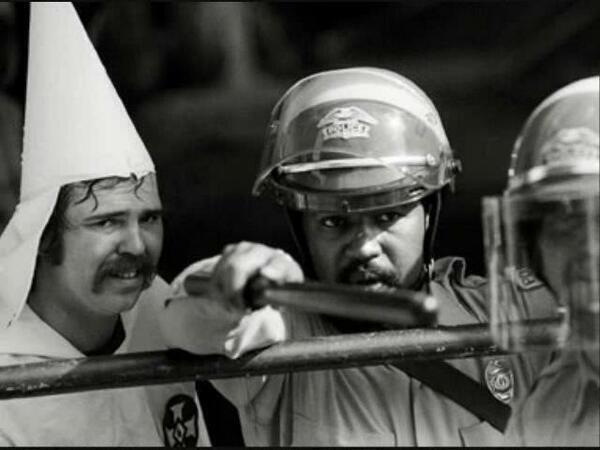 Un poliziotto nero protegge un membro del KKK, mentre i manifestanti stanno chiudendo su di loro in una manifestazione ad Austin, Texas, 1983
