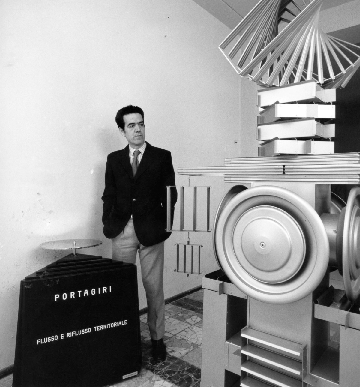 Ugo Ugo alla Galleria Comunale nei primi anni 70 con l'opera Portagiri (1970) di Vincenzo Agnetti e, alla sua destra, una sua scultura di fine anni 60