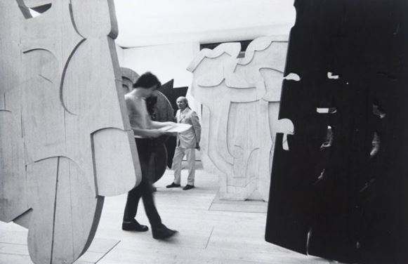 Pietro Consagra al centro dei suoi frontali in legno , 1960. Fotografia di ugo Mulas