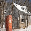 Stazione di servizio abbandonata nella neve e nella luce solare di inverno lungo il bordo della strada, americana rustica degli anni 60