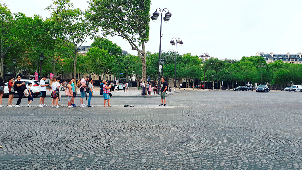 Turisti in fila in mezzo alla strada per fare la foto all'Arc de triomphe