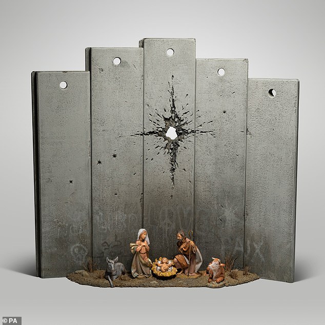 The 'Scar of Bethlehem' (pictured) features a nativity scene with Mary and Joseph and the baby Jesus - but instead of a star hanging over the crib, there is what appears to be a large bullet hole piercing an imposing grey wall