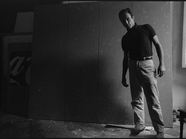 Mario Schifano nel suo studio davanti all’opera “Qualcos’altro”, Roma 1962