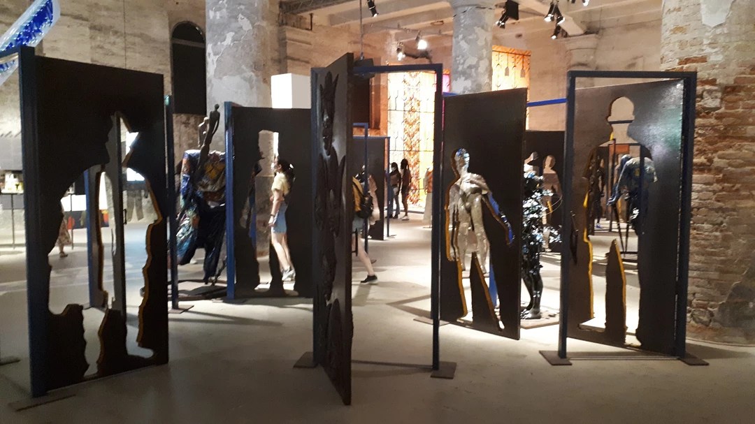 Ad aprire la #mostra alle Corderie Dell'Arsenale, l'installazione "Alasiri" (custode dei segreti) dell'artista nigeriano Peju Alatise. Composta da 40 porte e 13 figure umane, rappresenta la diversità delle identità e le barriere che spesso si frappongono tra loro.